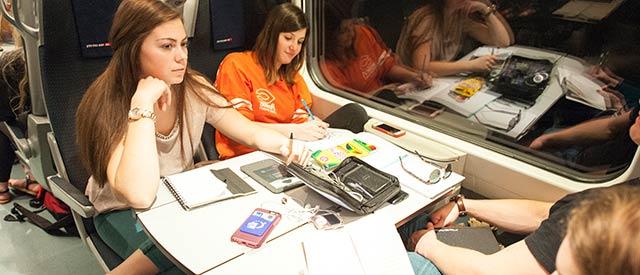 Female Carroll students writing while traveling on a train