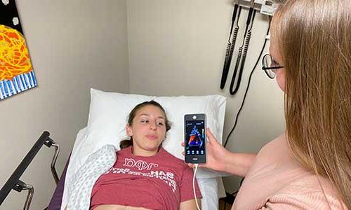 a woman in a hospital bed holding up a cell phone.