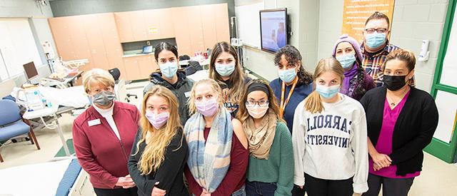 一群戴着口罩的学生在护理教室里.