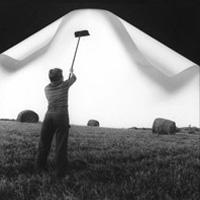 Surreal photograph of a man wall papering a folding sky