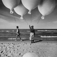 Surreal photograph of a beach scene with a group of balloons